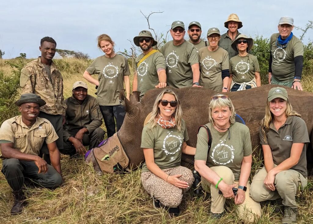 Wild Tomorrow rangers and volunteers pose alongside a sedated rhino who has been dehorned to deter poachers.